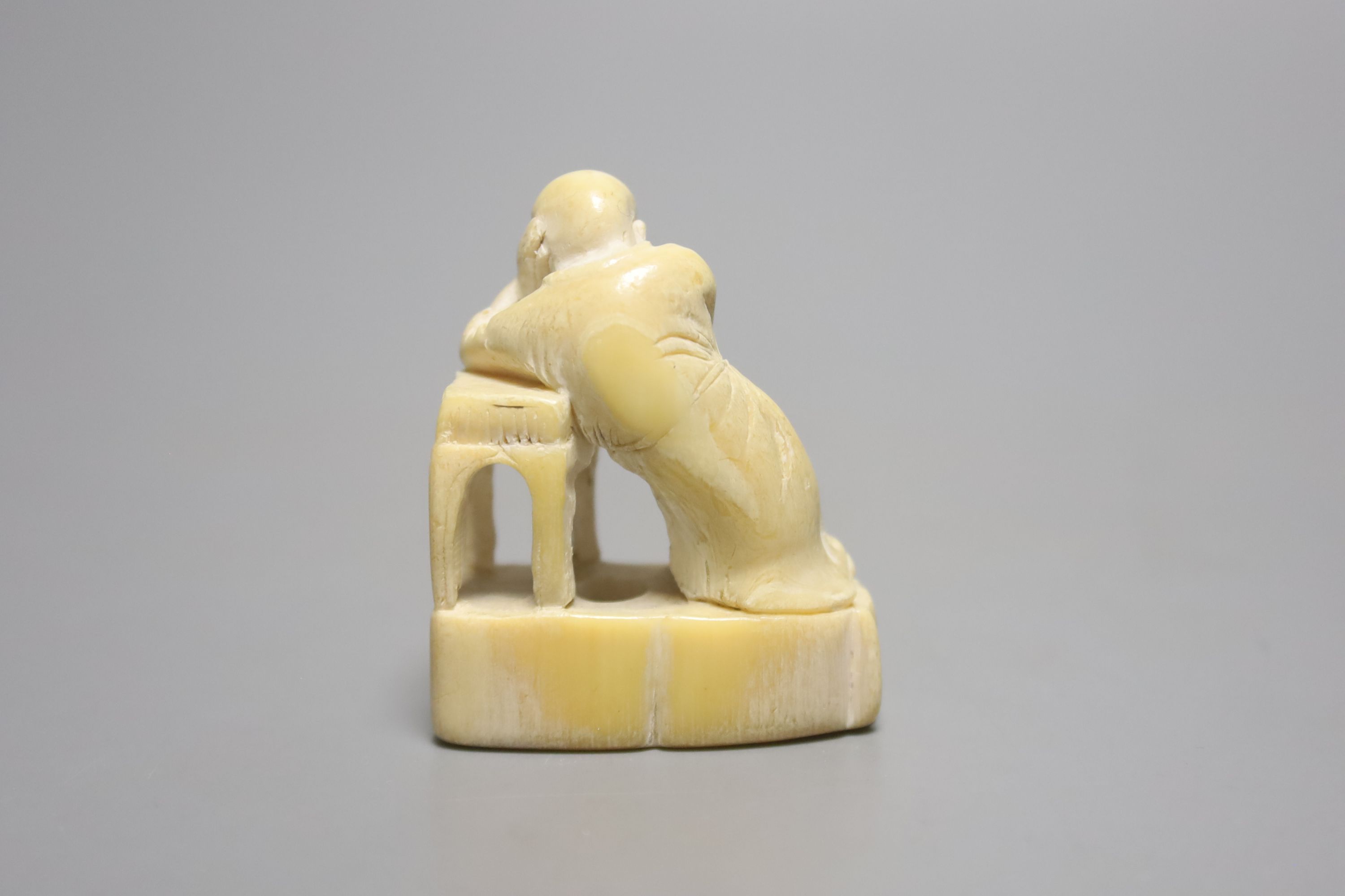 A Japanese ivory netsuke of a sleeping scholar at his table, 18th/19th century, height 4.5cm